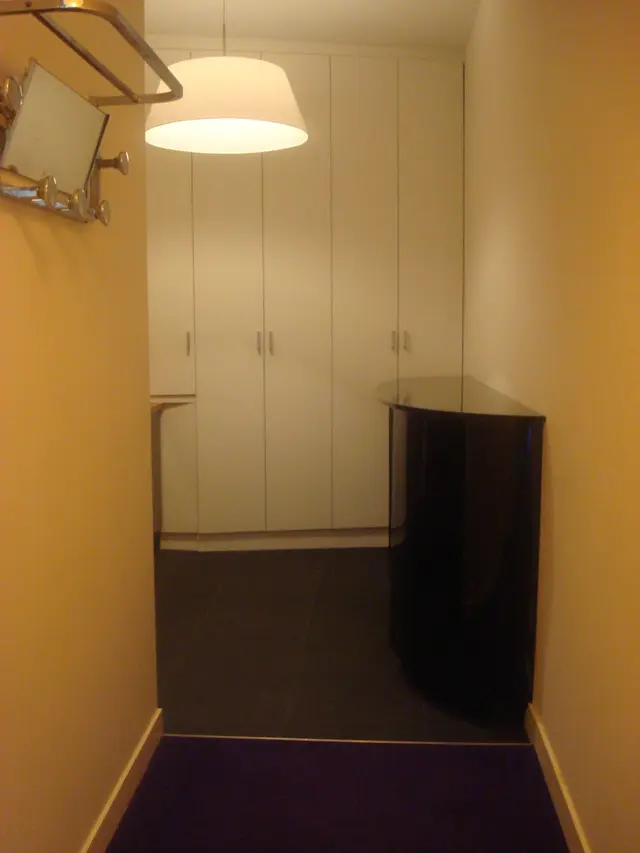 Zwarte ronde archiefkast met spiegel en kapstok in hal