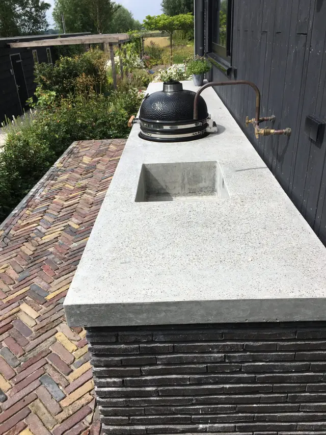 Betonnen werkblad met spoelbak en kamado bbq, gezien over de tuin