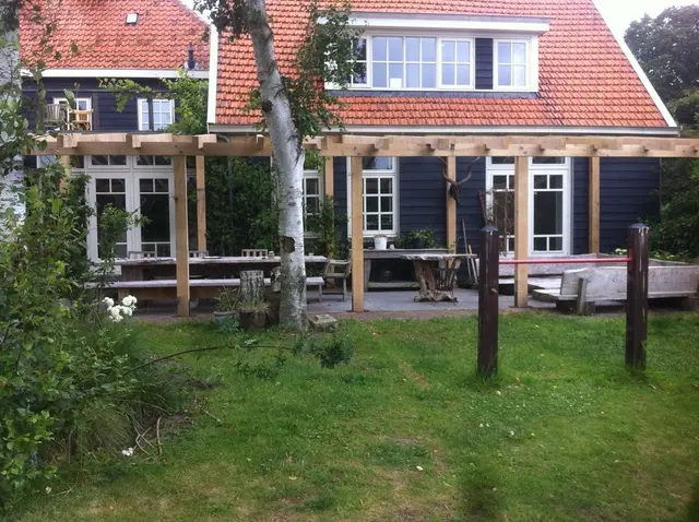 Eiken pergola met tuinmeubels tegen woonhuis