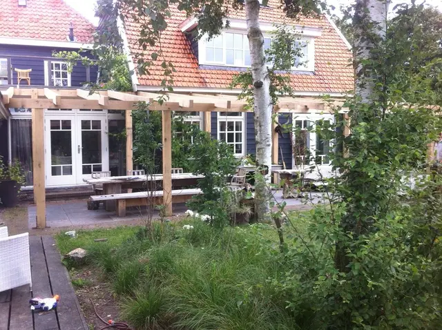Eiken pergola gezien vanuit de tuin tussen begroeiing