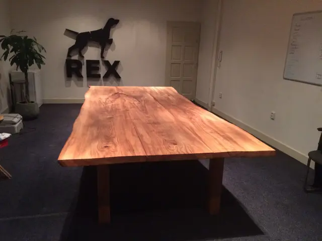 Iepenhouten tafel in kantoorruimte met logo aan wand