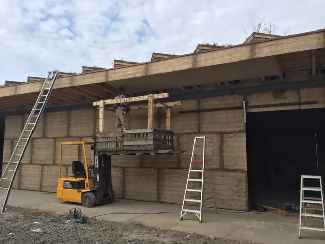 Hoogwerker hijst bekistingspaneel langs aarden wand