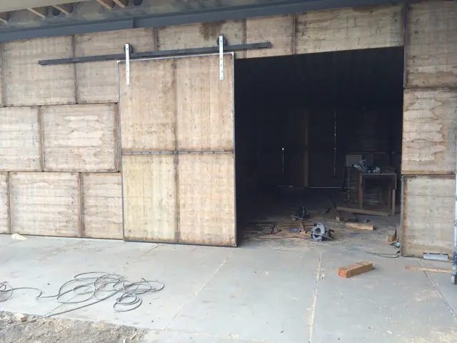 Houten schuifdeur in wand van gestampte aarde