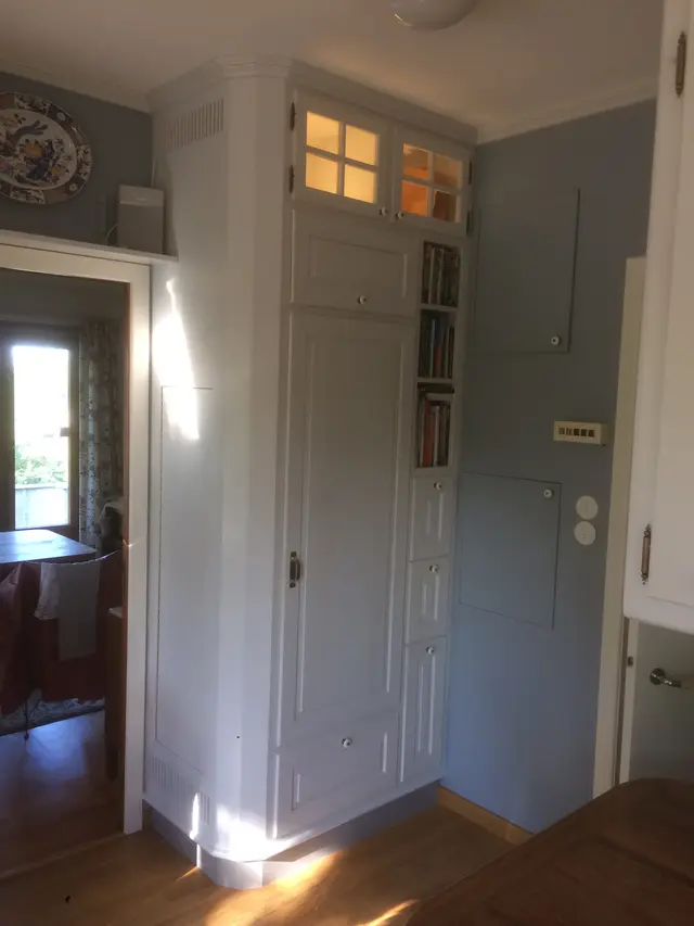Witte hoekkast met glazen bovendeuren en boekenrek