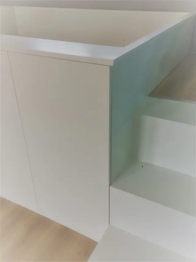Detail van wit inbouwbed met houten trapopgang
