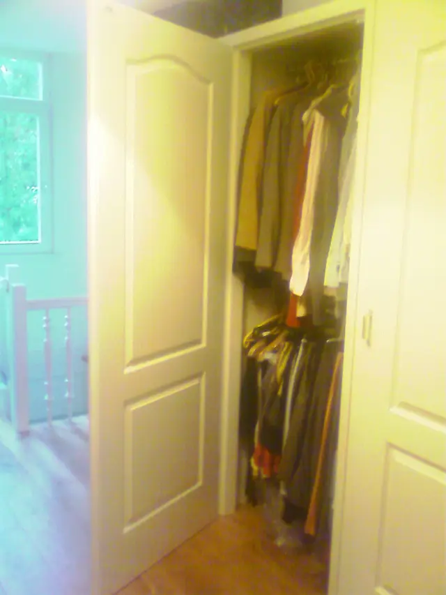 Open inbouwkast met hangende kleding aan garderobestang