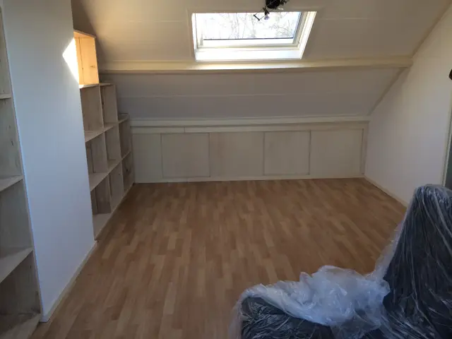 Zolderkamer met inbouwkasten onder dakraam, in aanbouw