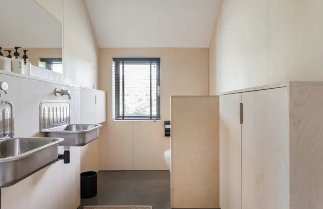 Badkamer met dubbele RVS wastafel en toilet