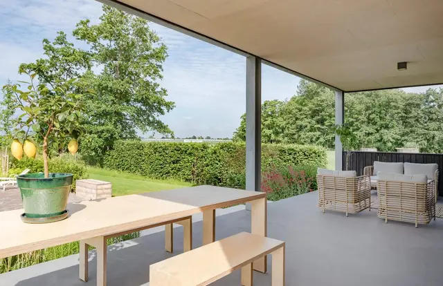 Overdekt terras met houten tafel en bankjes