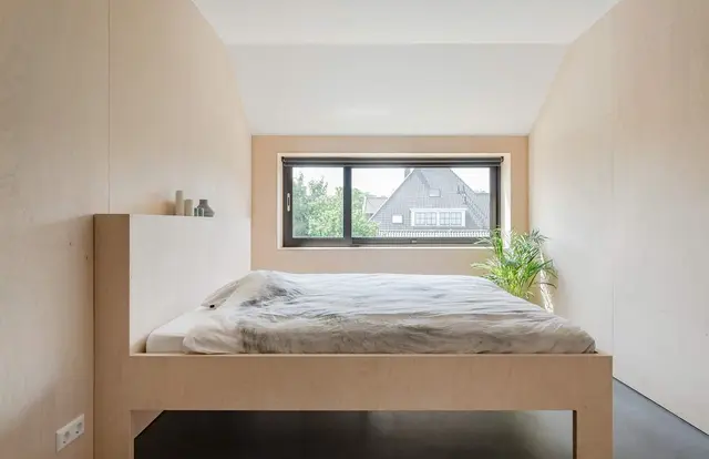 Slaapkamer met houten bedframe onder dakraam