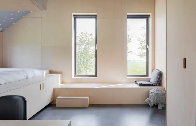 Zolderslaapkamer met vast houten bed en zitbank