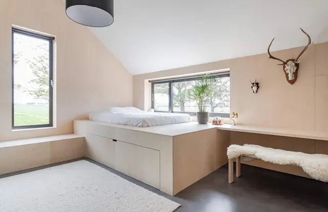 Slaapkamer met vast bed en hertengewei aan wand