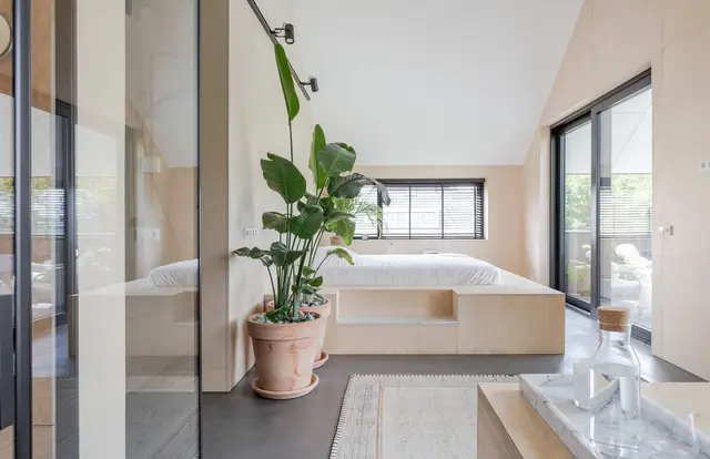 Slaapkamer en suite met glazen scheidingswand en plant