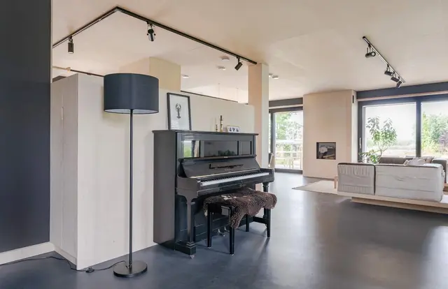 Woonkamer met piano en industriële spotverlichting