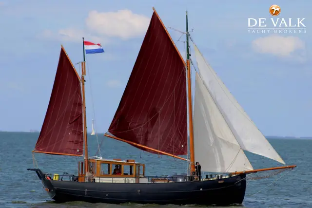Klassiek zeiljacht met roodbruine zeilen op zee