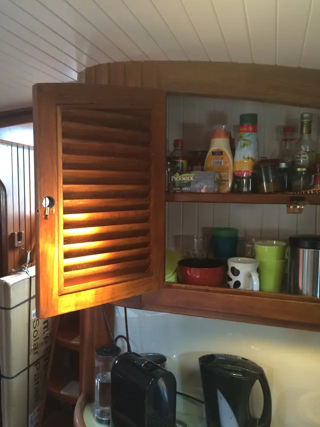 Open teakhouten kastje met voorraad en servies