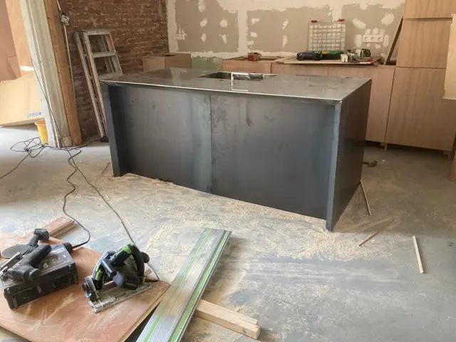 Stalen keukeneiland met RVS blad tussen houten kasten