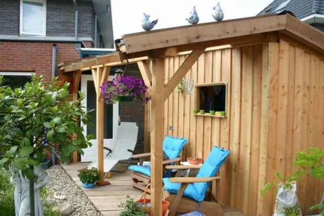 Houten pergola met hangende bloembak bij tuinhuis