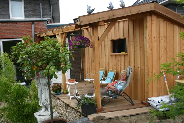 Vrouw ontspant in ligstoel op veranda van tuinhuis