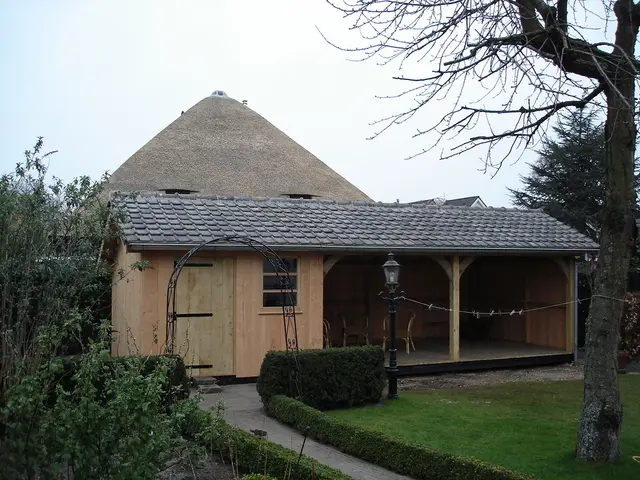 Houten schuur met rieten kap, zijaanzicht met veranda