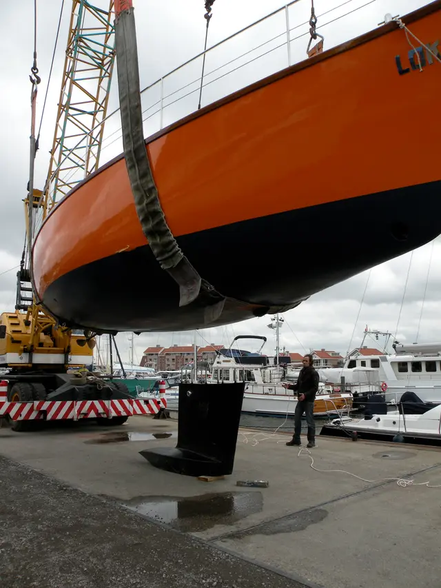 Zeiljacht met kiel hangend aan kraan in jachthaven