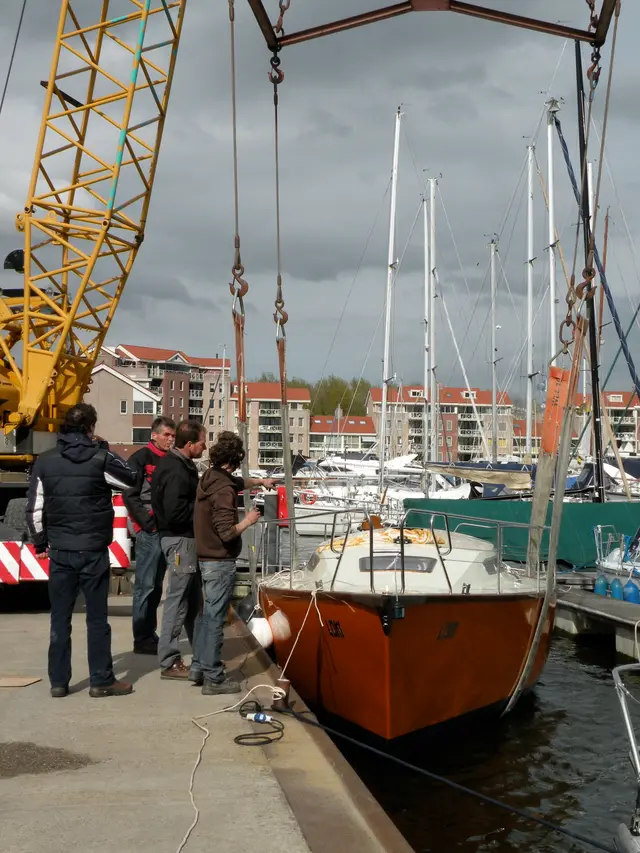 Mannen bij te water gelaten zeiljacht aan kraan