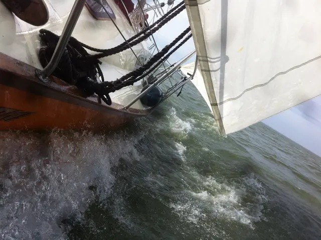Boeg van zeiljacht ploegend door golven onder zeil