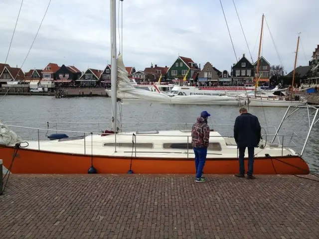 Zeiljacht afgemeerd bij vissersdorp met opstappers