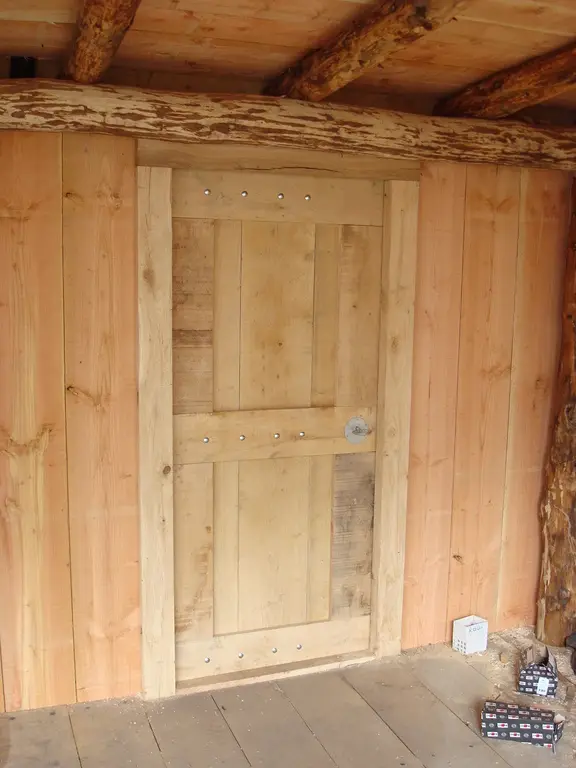 Houten deur in veranda met ruwe boomstam-balken