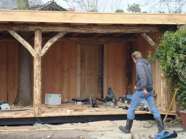 Houten veranda met boomstam-kolommen, bouwvakker aan het werk