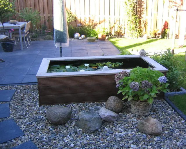 Houten vijverbak met waterlelies op terras