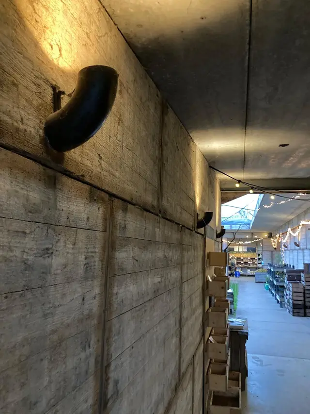 Wandlamp op houten paneel met zicht op winkelgang